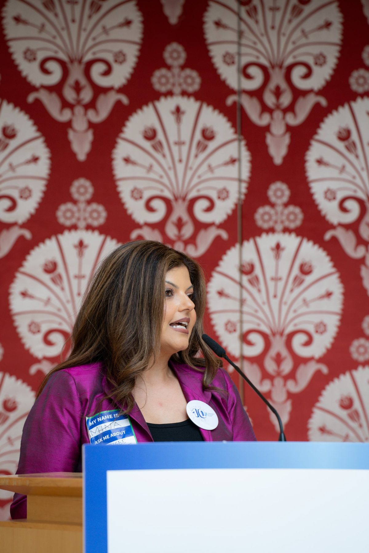 Mina Sharif speaking at a podium microphone
